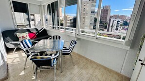 A balcony with a dining area, including a table and chairs, and a sofa with cushions. - A29 - Wonderful urbanization in Cala de Finestrat (Cala de Finestrat)
