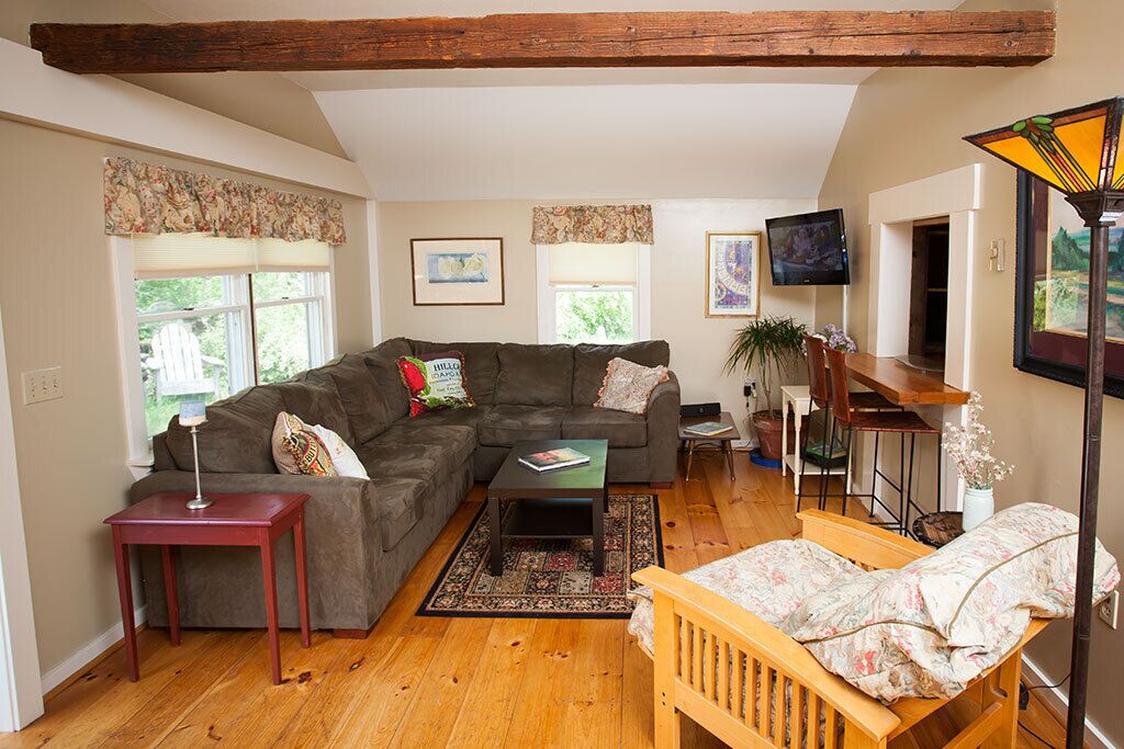 A cozy living room with a sectional sofa, a small coffee table, a wooden bench, and a TV mounted on the wall.