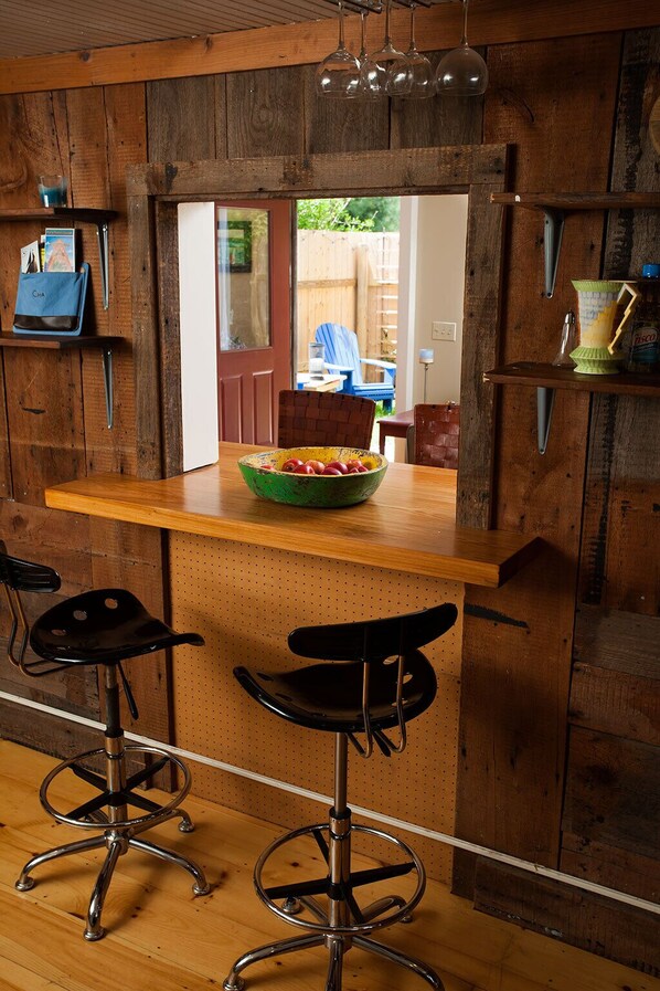 A rustic bar area with wooden walls, a wooden countertop, and two black bar stools.