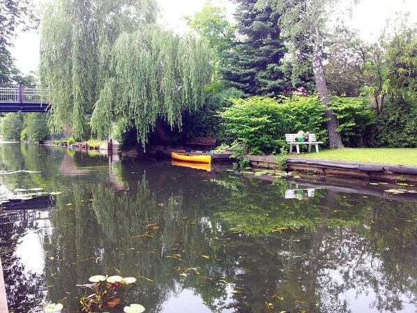 Un cadre paisible au bord de la rivière, avec un bateau en bois, un banc et une végétation luxuriante.