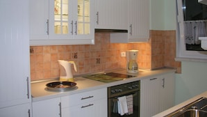 A kitchen with white cabinets, a coffee maker, and a stove. - Domizil Neu Venedig (Berlin)