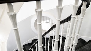 A staircase with white balusters and a black handrail. - Kelpies Serviced Apartments (Falkirk)