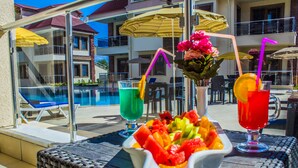 A poolside setting with a wicker table, a bowl of fruit, and two drinks with straws. -  Form Thermal Hotel & Spa Kazdağları (Edremit)