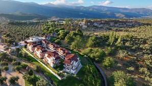 An aerial view of a residential area with multi-story buildings, surrounded by greenery and mountains in the background. -  Form Thermal Hotel & Spa Kazdağları (Edremit)