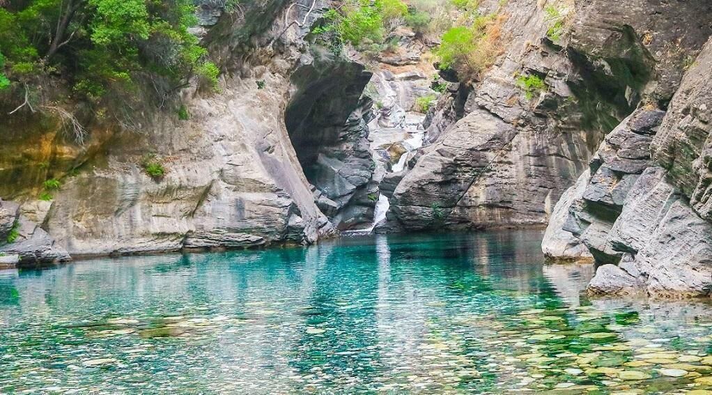Una formación rocosa natural con una piscina de agua cristalina.