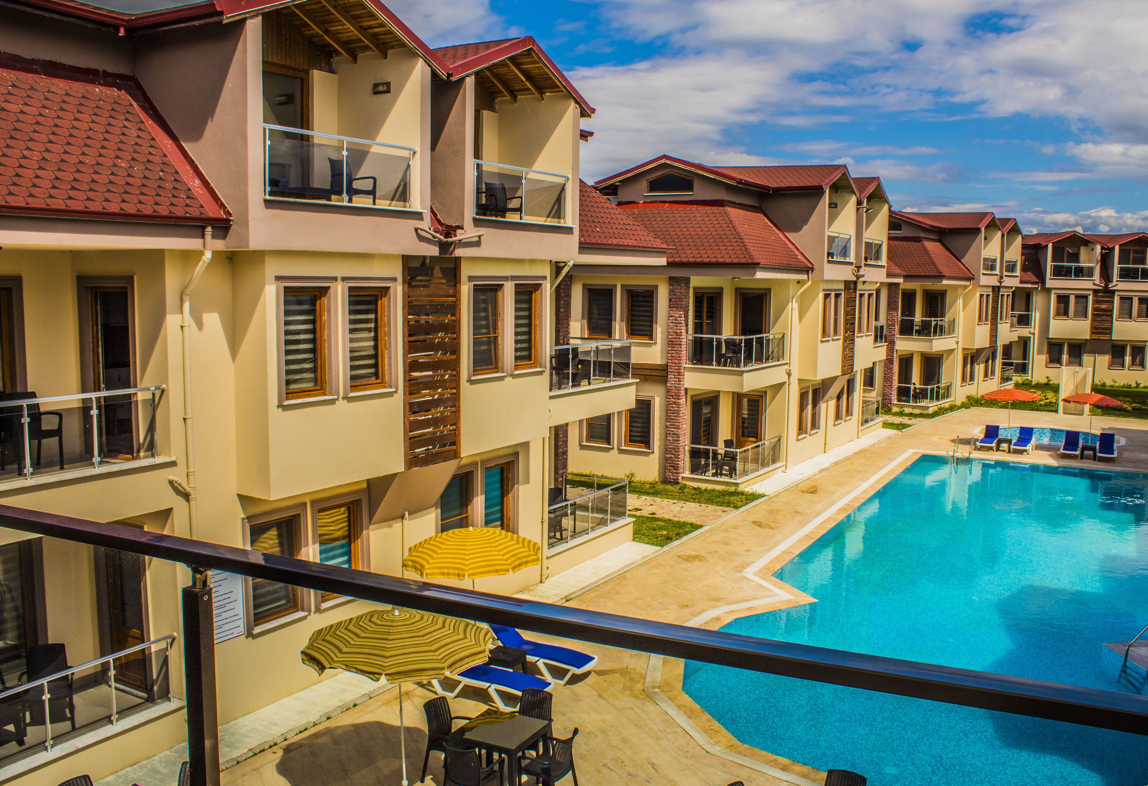 Un hotel de varios pisos con balcones, piscina y zonas de estar al aire libre.