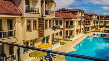 Un hotel de varios pisos con balcones, piscina y zonas de estar al aire libre.