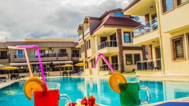 A poolside view with a fruit tray and drinks, a pool, and a building with balconies and outdoor seating. -  Form Thermal Hotel & Spa Kazdağları (Edremit)
