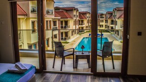 A balcony with a pool view, a bed, and two chairs. -  Form Thermal Hotel & Spa Kazdağları (Edremit)
