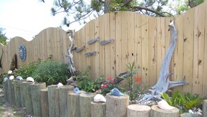 Een houten hek met decoratieve details en een tuin met planten en rotsen.