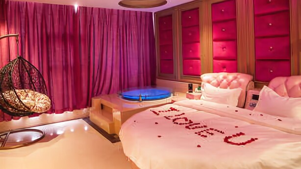 A modern bedroom with a large bed, a hanging chair, and a blue circular platform. - Jinyi Hotel (Sanming)