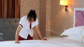 Una habitación de hotel con una cama bien hecha, un cabecero y una lámpara de pared.