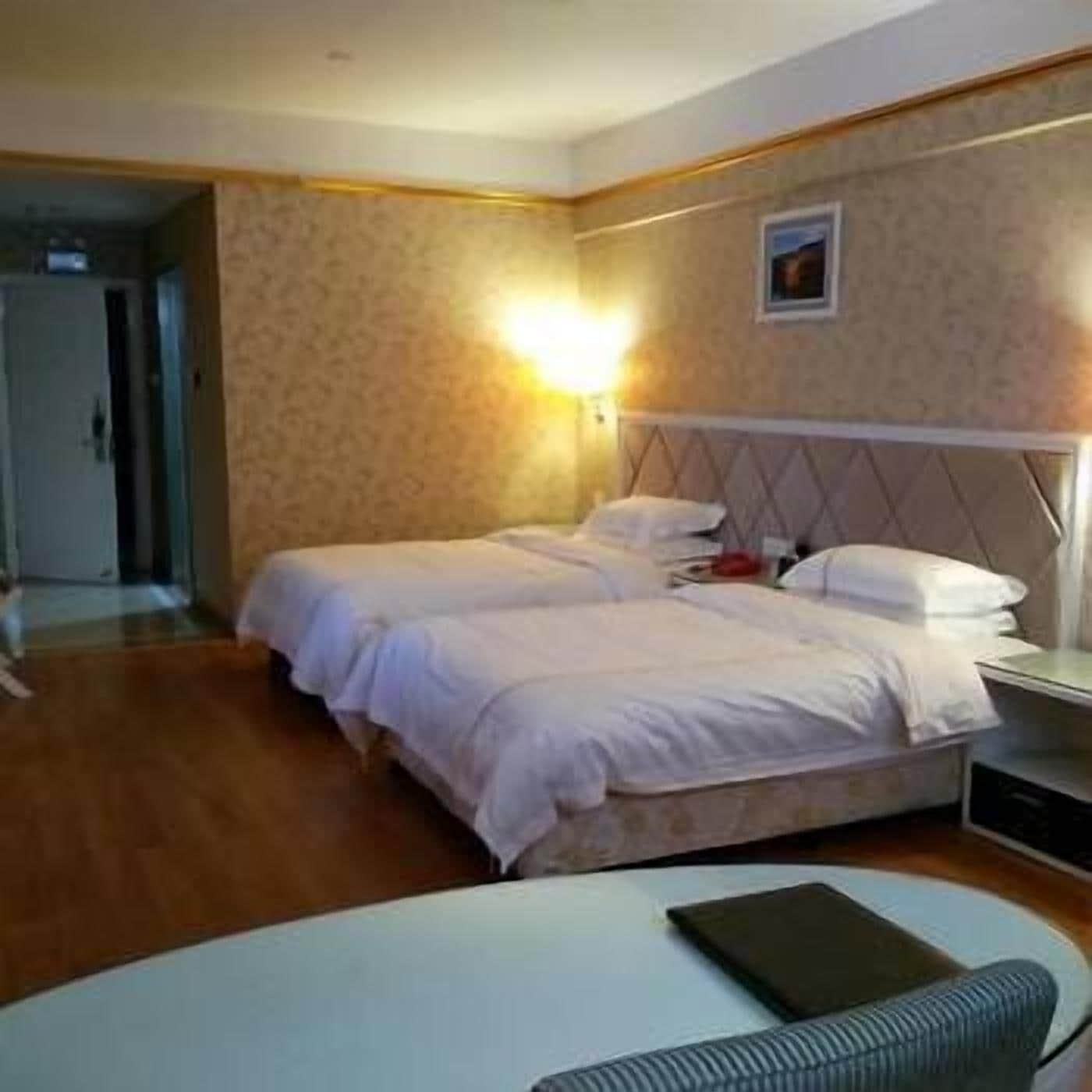 Une chambre d’hôtel avec deux lits, une table de chevet et une petite table ronde.