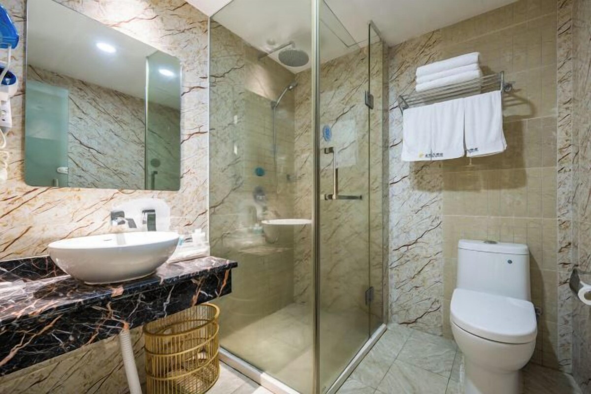 Une salle de bain avec un lavabo en marbre, une douche à parois de verre et des toilettes.