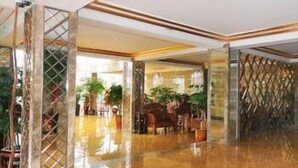 A spacious lobby with a polished marble floor, a seating area with a table and chairs, and decorative plants. - Jinyi Hotel (Sanming)