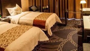 A hotel room with two beds, a nightstand, a lamp, and a large window with curtains. - Jinyi Hotel (Sanming)