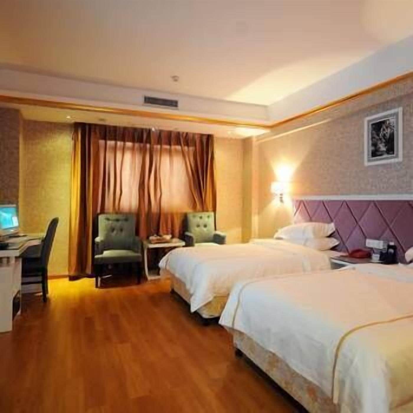 Habitación de hotel con dos camas, un escritorio con computadora y una silla.