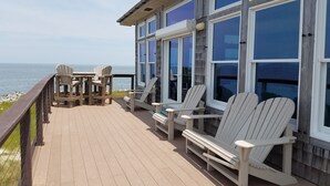 A wooden deck with Adirondack chairs and a table overlooking the ocean. - Hooligan Sunset:  Waterfront deck, sunsets, private boat dock. (Ocracoke)