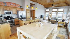 A spacious kitchen with wooden cabinets, a large island, and modern appliances. - Hooligan Sunset:  Waterfront deck, sunsets, private boat dock. (Ocracoke)