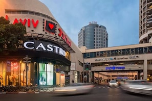 A modern building with a curved facade, a prominent 'CASTRO' sign, and a 'RENUAIR CENTER' sign above. - Sweethome26 - Dizengoff with Terrace (Tel Aviv)