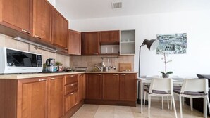 Una cocina moderna con armarios de madera, microondas, lavaplatos y comedor con sillas y mesa.