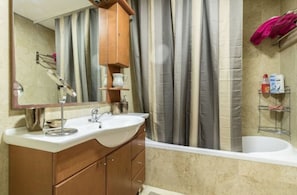 A bathroom with a double sink, a mirror, a wooden cabinet, a shower curtain, and a bathtub. - Sweethome26 - Dizengoff with Terrace (Tel Aviv)