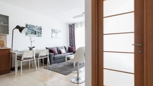 Una sala de estar moderna con comedor, un sofá, una mesa de centro y una lámpara.
