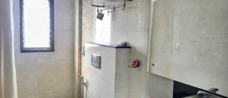 A bathroom with a toilet, a shower, a sink, and a towel rack.