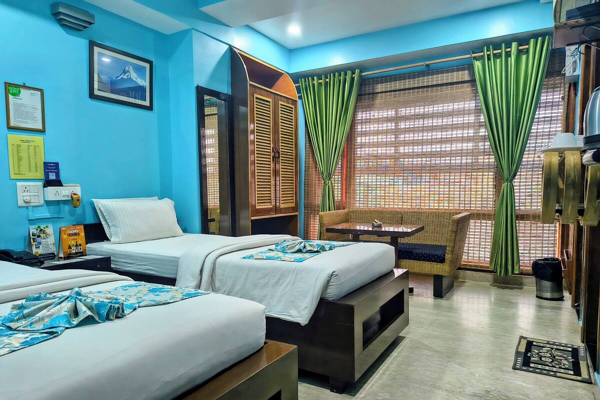 A hotel room with two beds, a sofa, a table, and a window with curtains.
