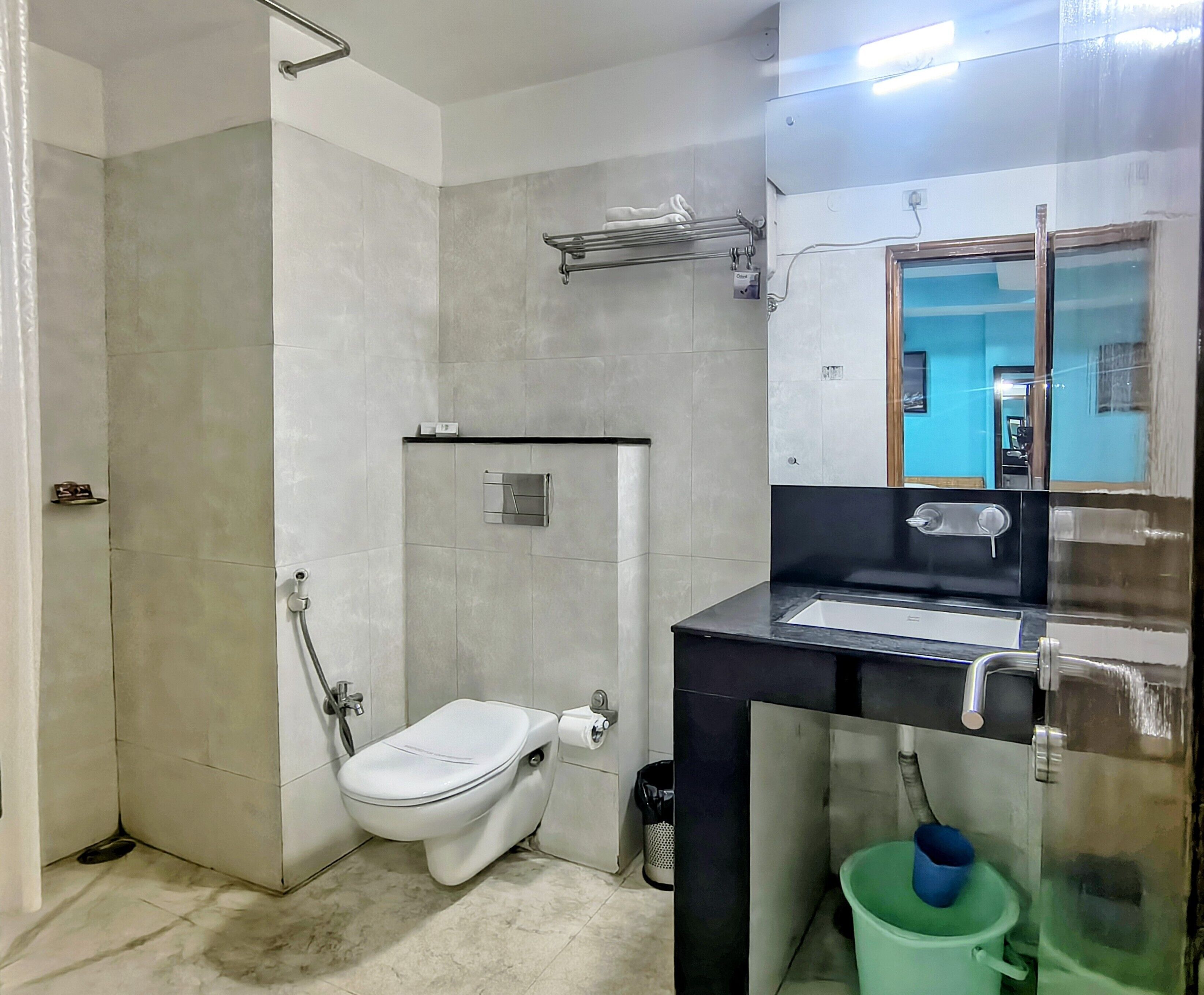 Een badkamer met toilet, douche, wastafel en spiegel.
