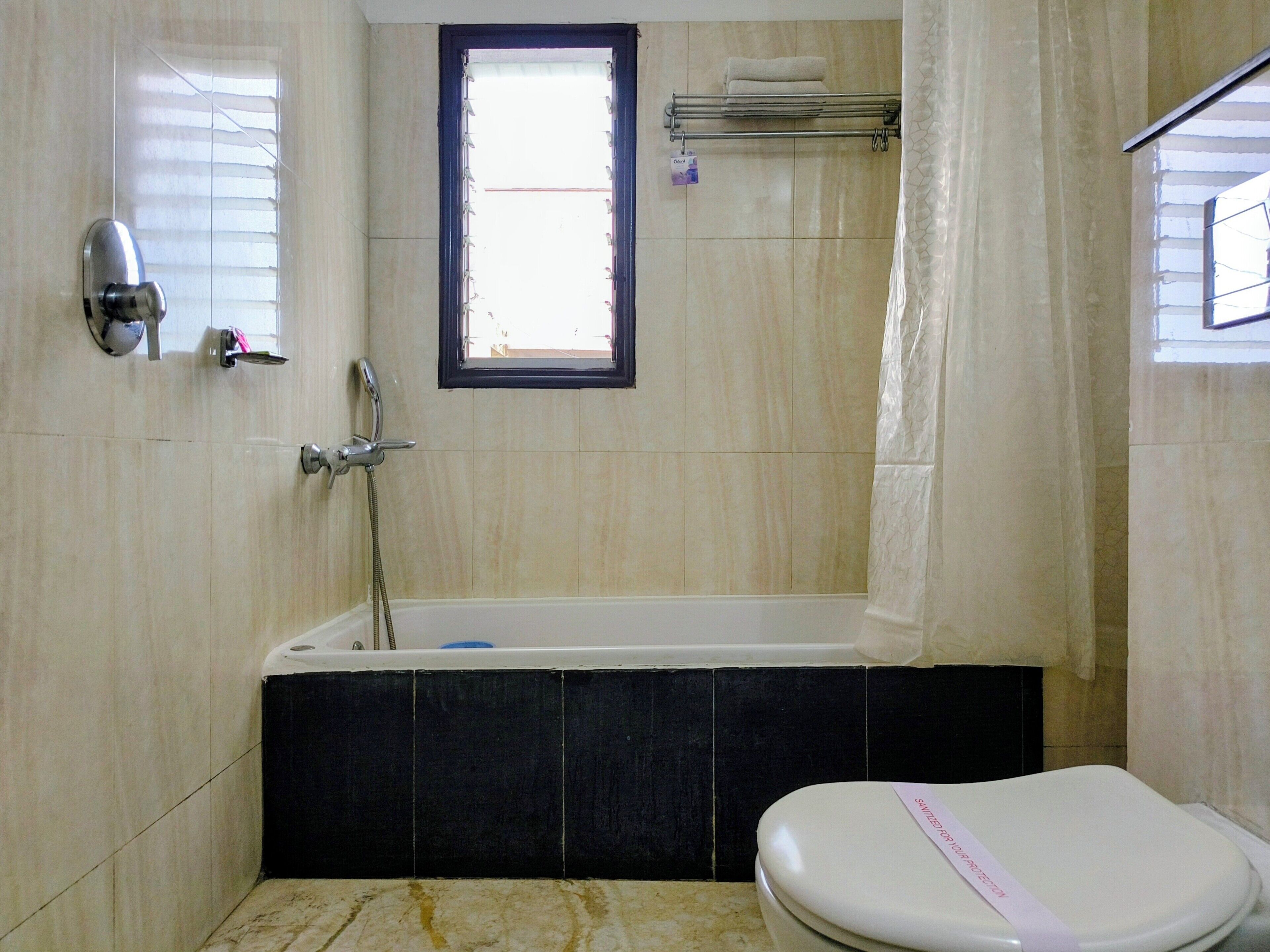 A bathroom with a bathtub, toilet, and a window.