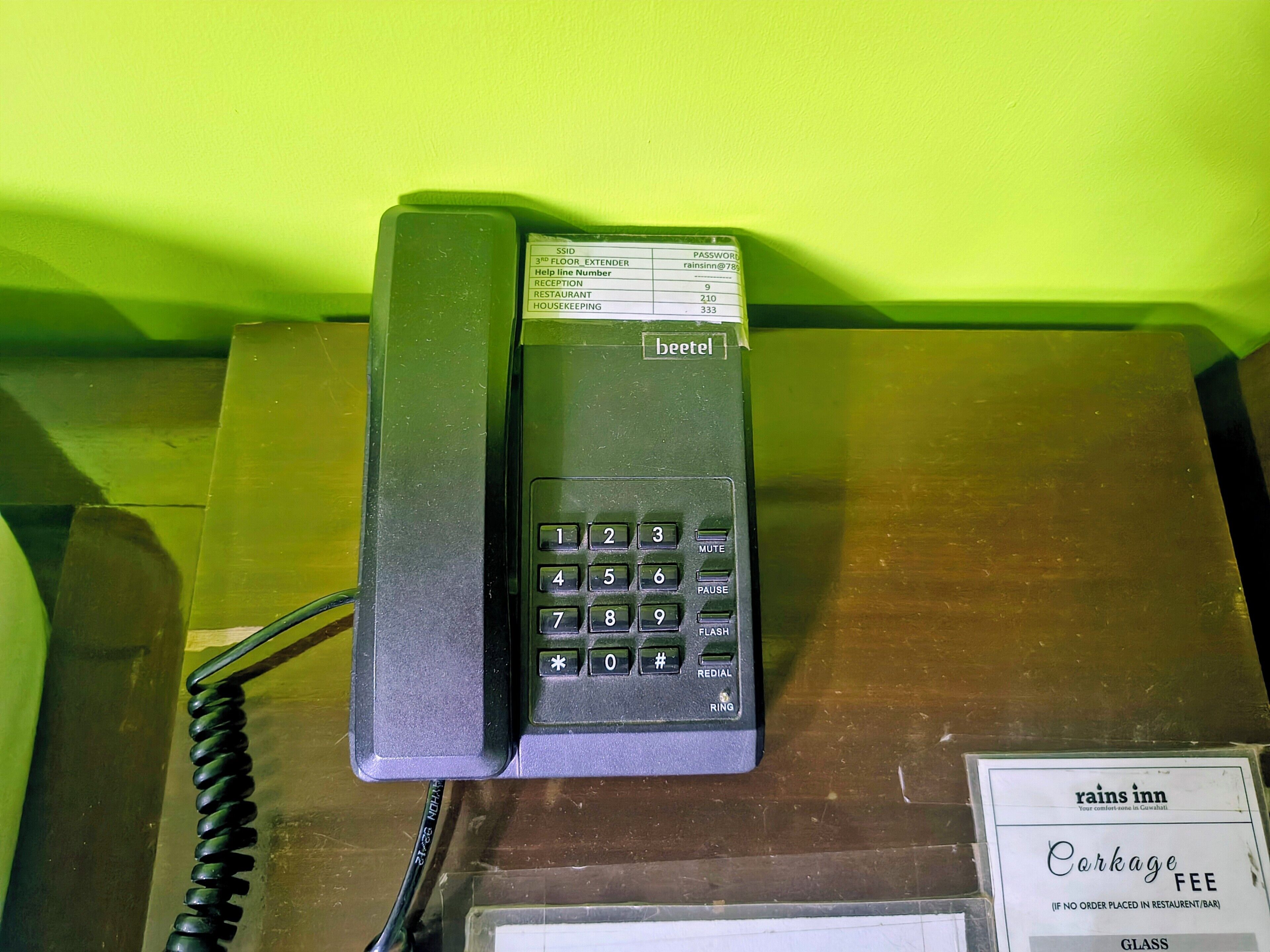 Ein schwarzes Telefon mit Tastatur und dem Schriftzug 'beetel' auf einer Holzoberfläche.