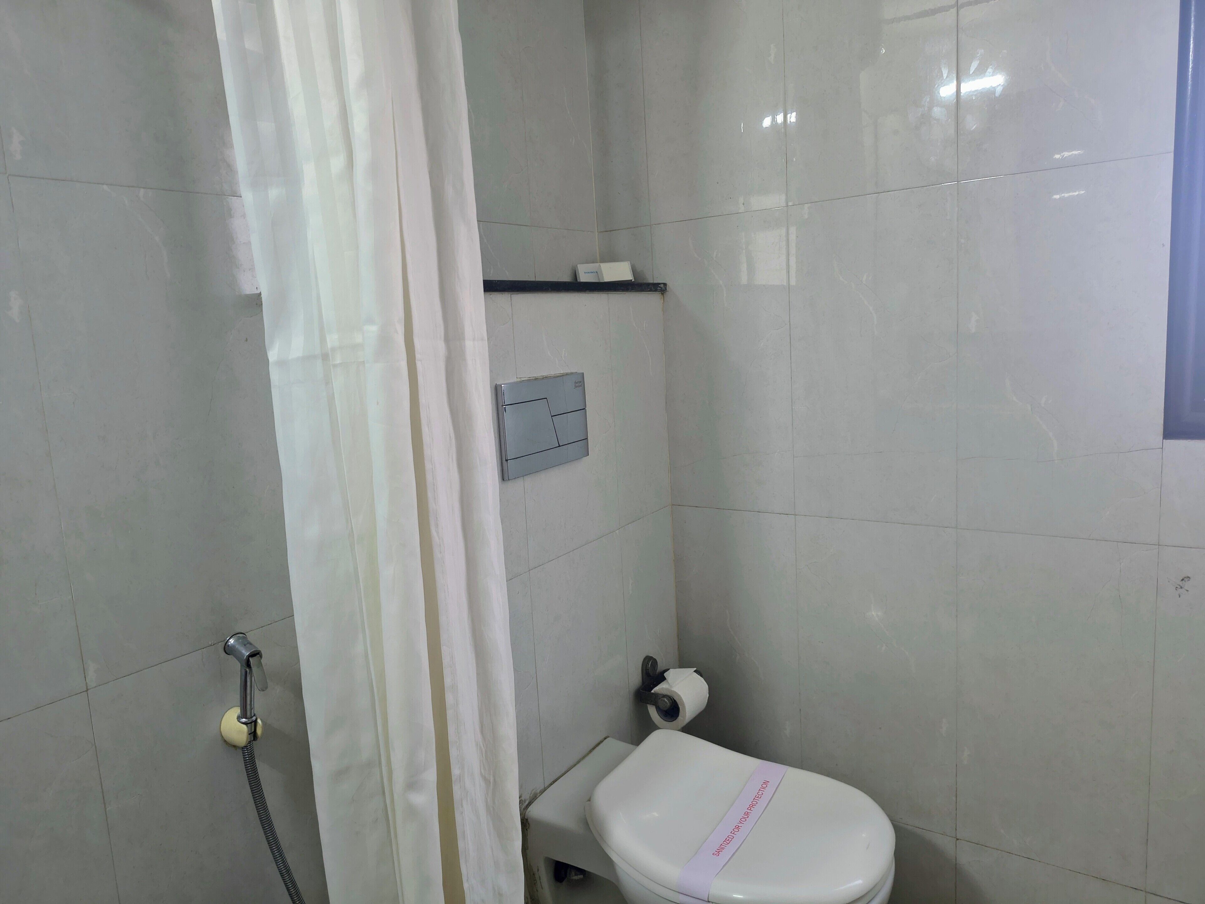 Un bagno con un water, una doccia e un portasciugamani.