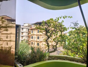 A multi-story building with balconies, surrounded by greenery and a clear sky.
