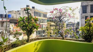 Un balcón con vistas a edificios, un árbol con flores rosas y un cartel de 'Glamour Cosmetics'.