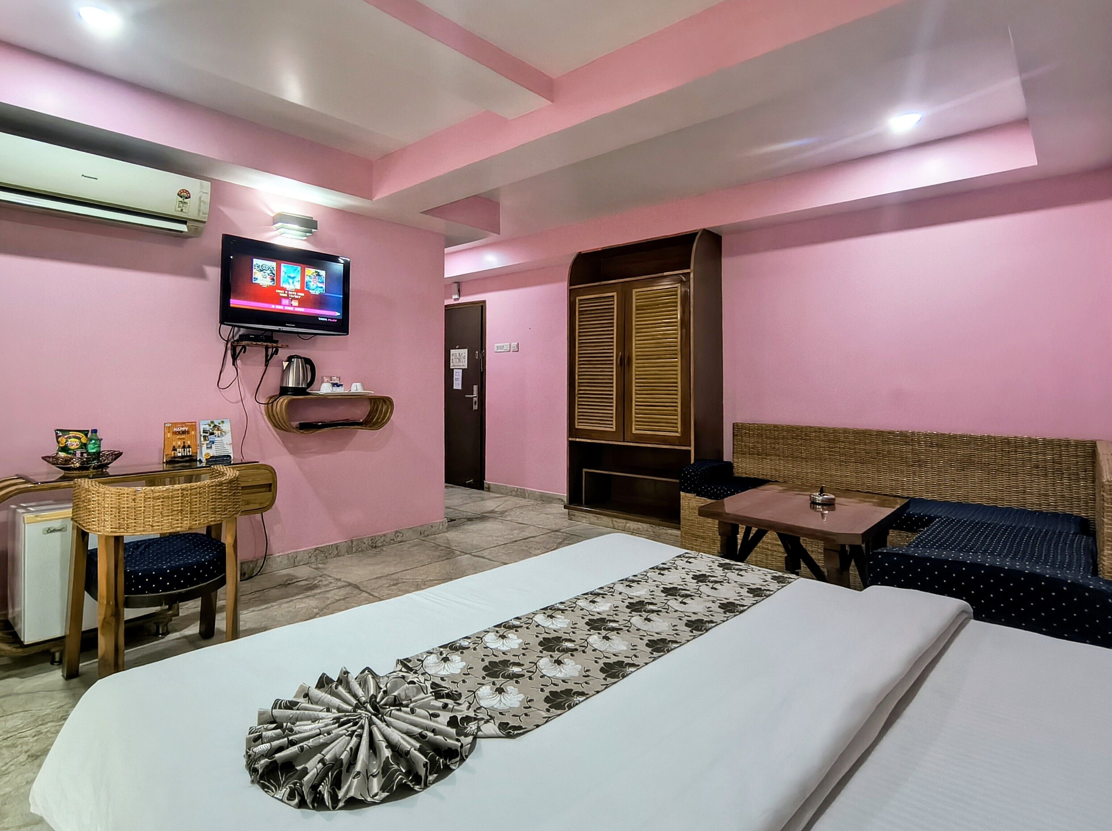 Una habitación de hotel con cama, televisión, escritorio, silla, sofá y armario.