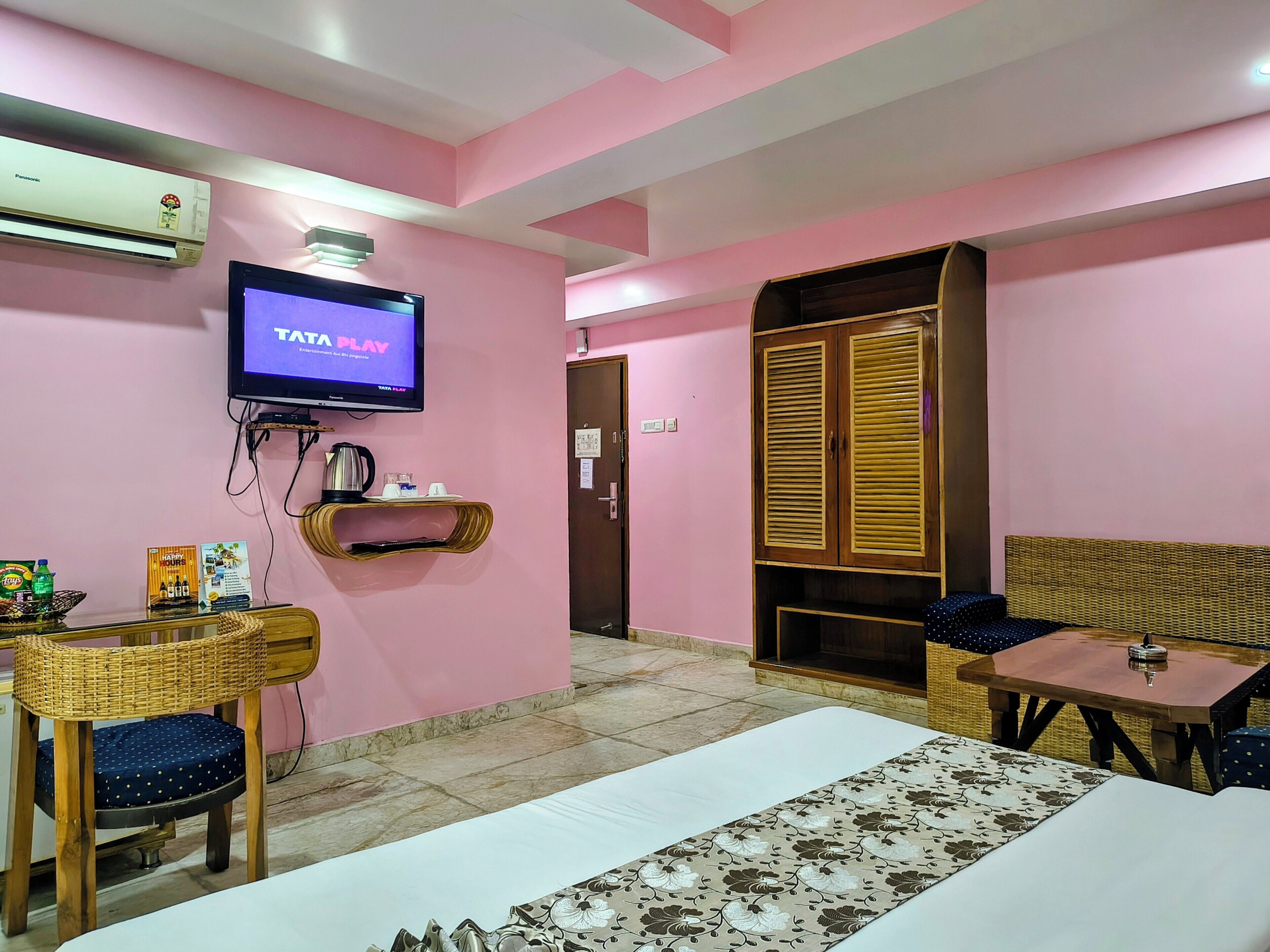 A hotel room with a bed, a TV, a wardrobe, a table, and a chair.