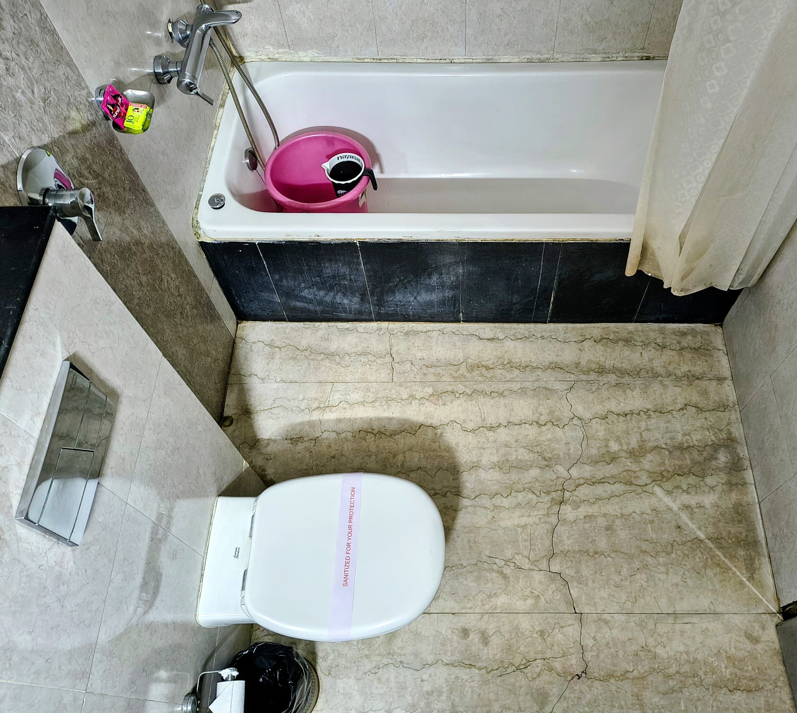 Une salle de bain avec des toilettes blanches, un bidet rose et un espace douche.