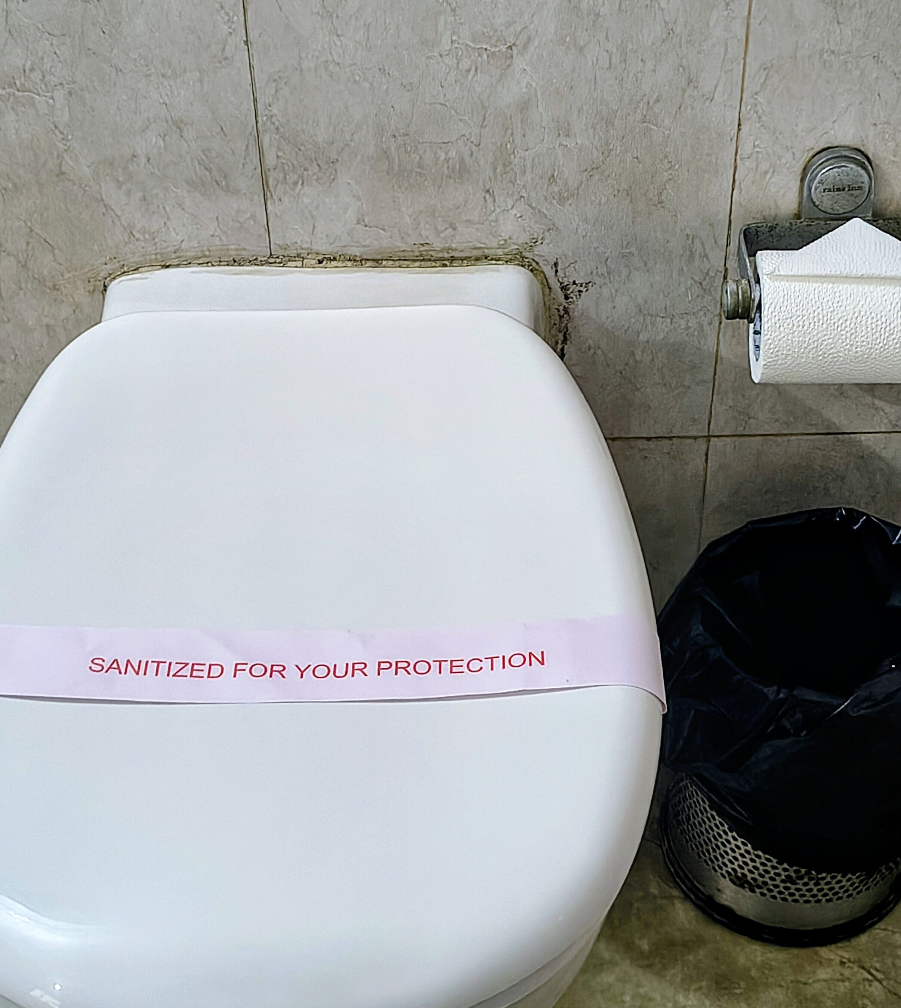 A toilet with a 'SANITIZED FOR YOUR PROTECTION' label.