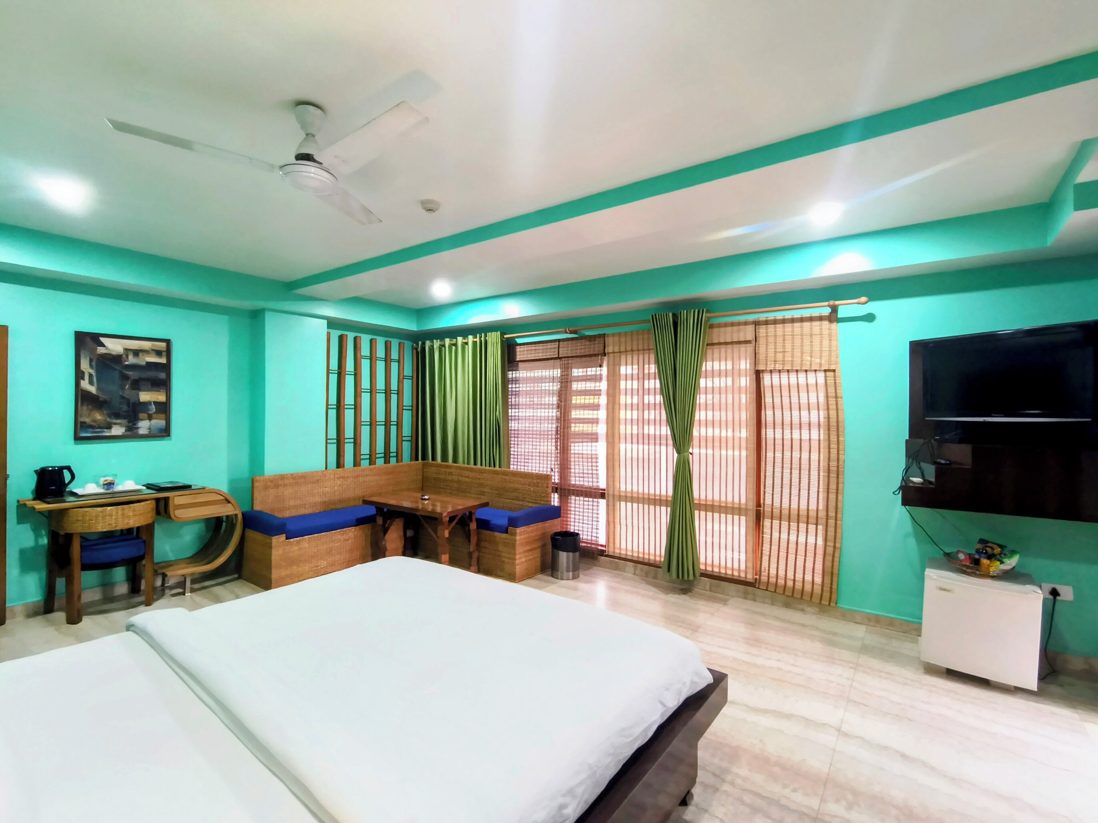 A hotel room with a bed, a desk with a chair, a television, and a window with curtains.