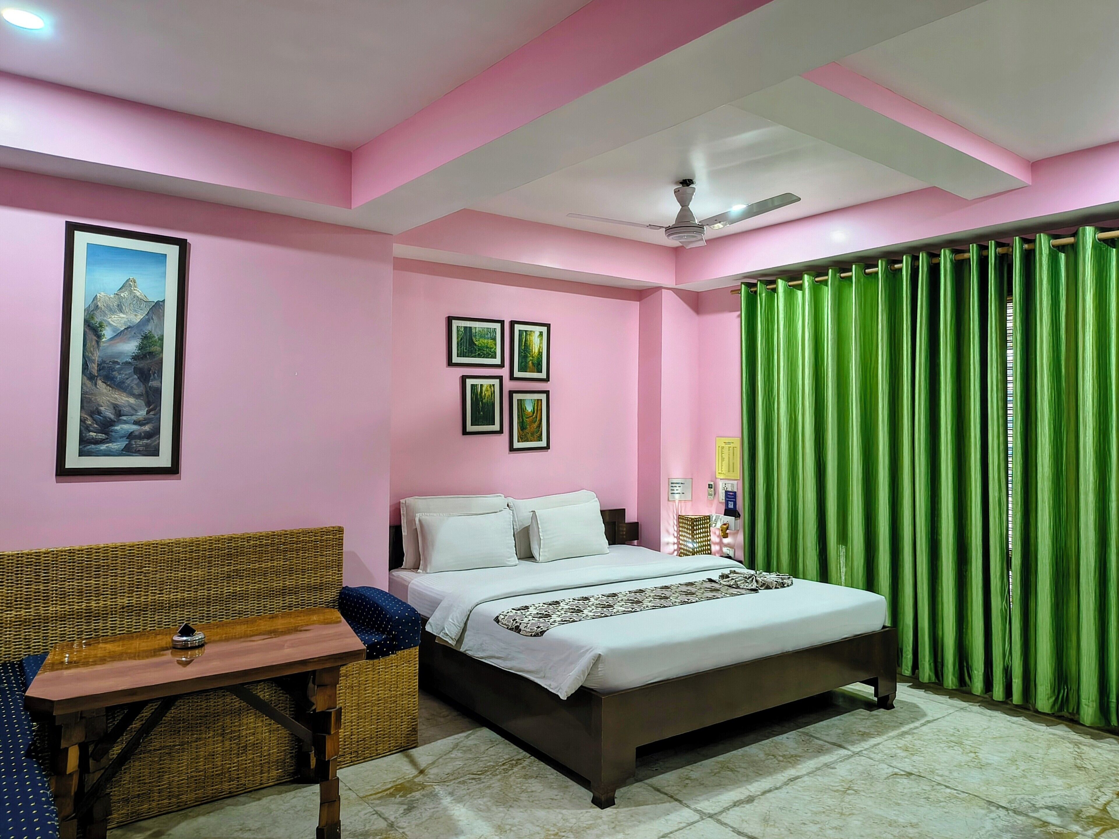 A bedroom with a bed, a desk, a chair, a ceiling fan, and a green curtain.