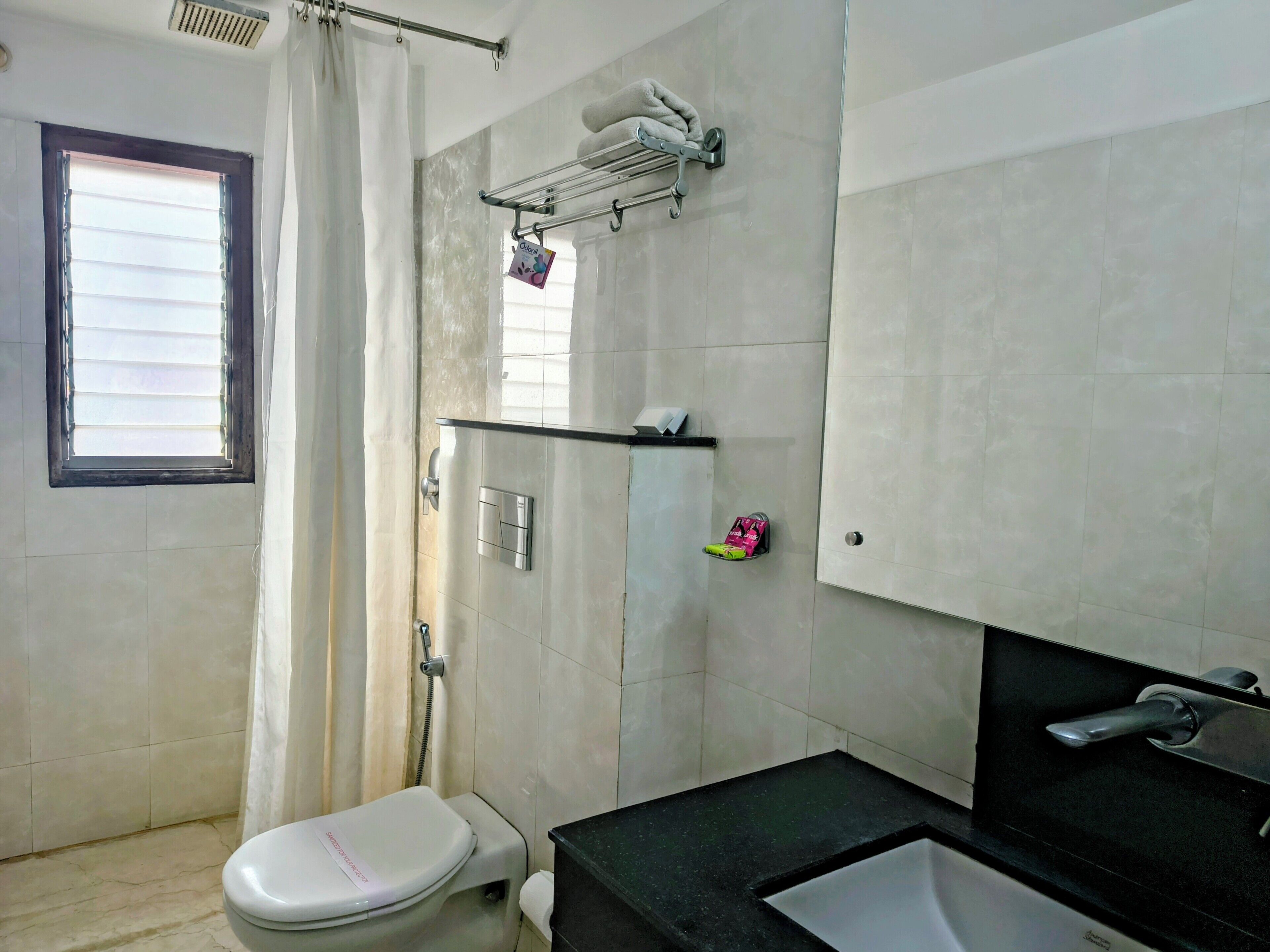 A bathroom with a toilet, a sink, a shower, and a towel rack.