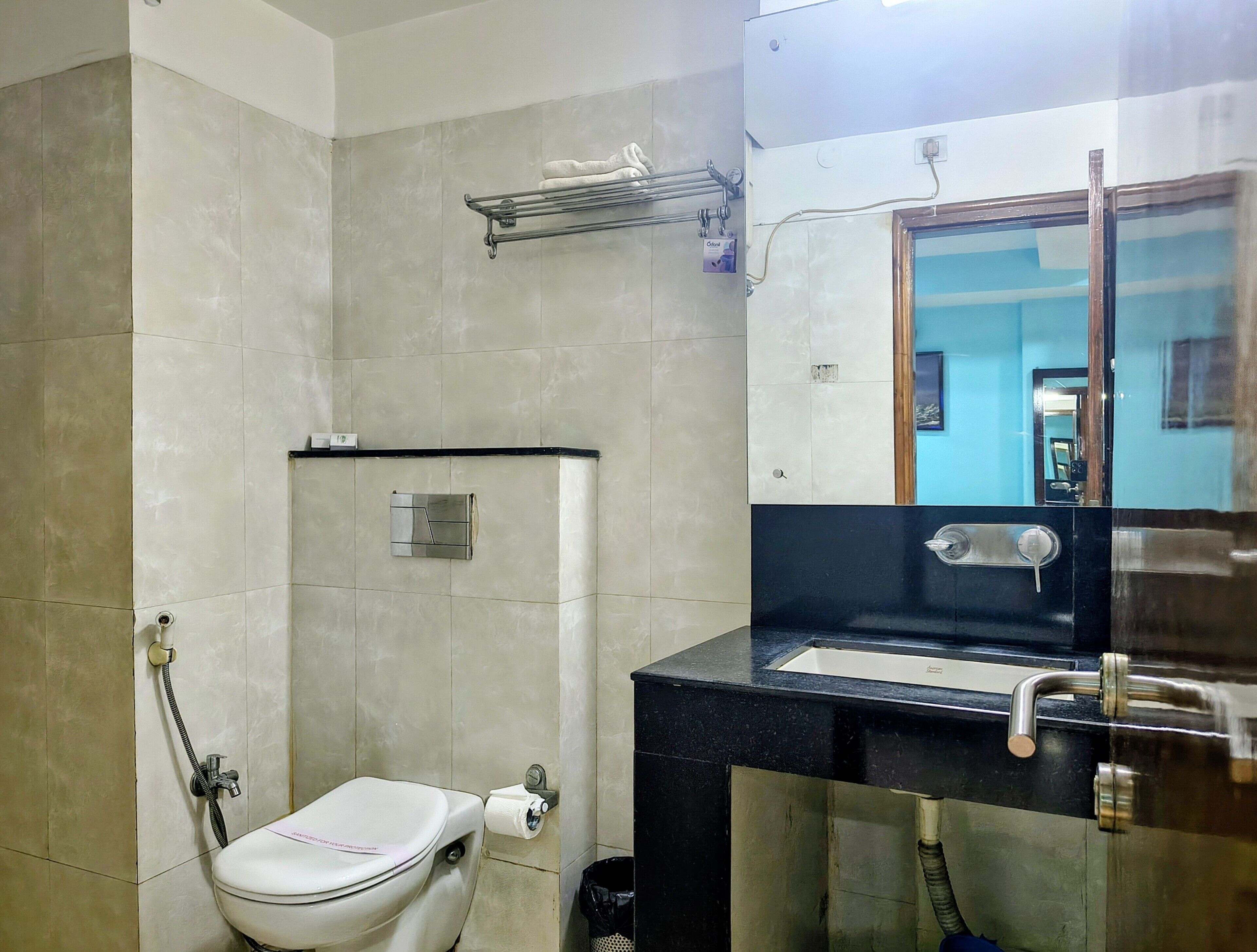 A bathroom with a toilet, shower, sink, and a mirror.