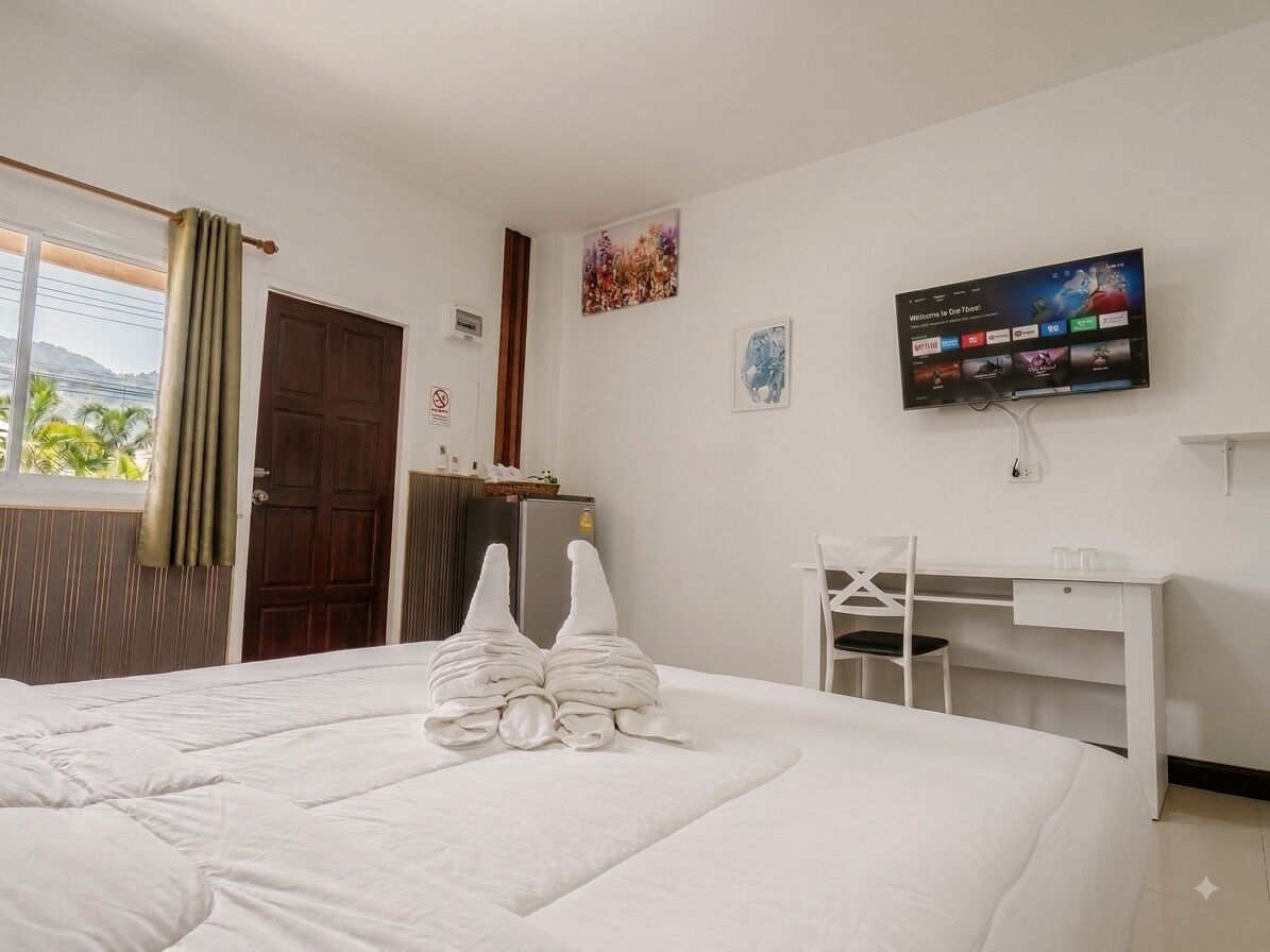 A hotel room with a bed, a desk, a television, and a window with curtains.