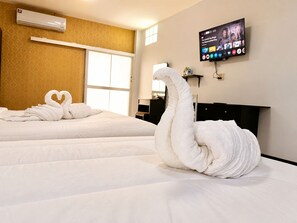A hotel room with two beds, a TV on the wall, and a large window.