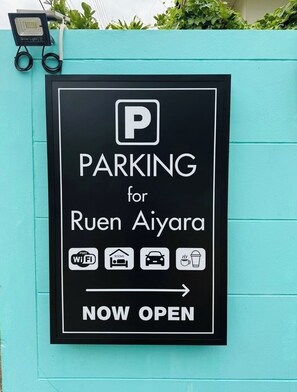 A sign indicating parking availability for Ruen Aiyara with amenities such as free WiFi, rooms, and a car wash.