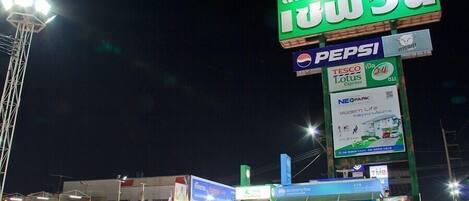 Une rue animée de nuit, avec une enseigne verte bien visible qui fait la publicité d’un magasin.