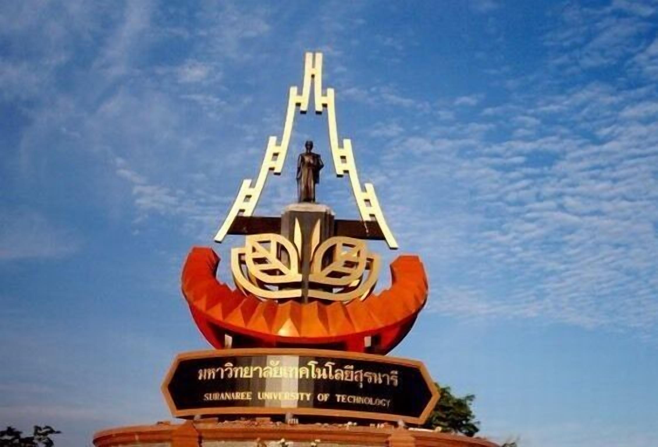 Ein Schild der Sukhothai University of Technology mit einem zentralen Wappen und einer Figur darüber.