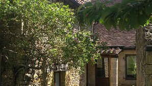 A stone building with a tiled roof, a wooden door, and a small window. - Rent Gite Casalissa house with heated pool in Perigord Noir, Sarlat (Castels)