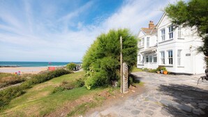 A white building with a stone pathway leading to a beach.